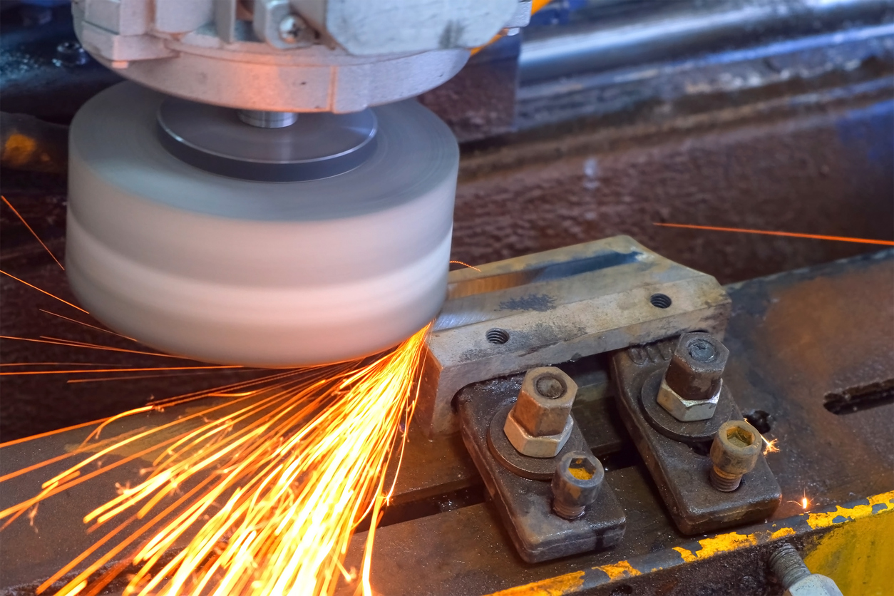 Amoladora industrial que crea chispas para pulir detalles de metal en una planta de carpintería metálica.