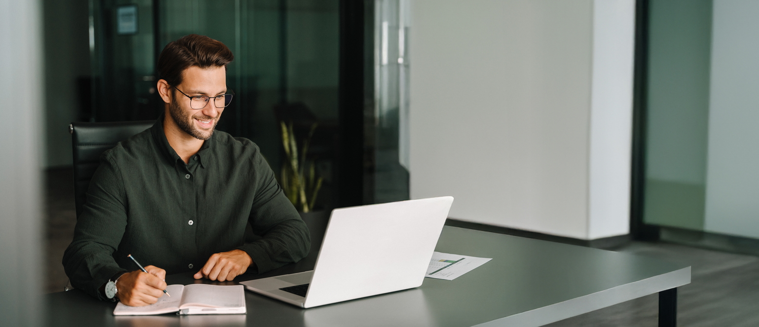 Hombre europeo de mediana edad usando un ordenador portátil para estudiar negocios, ver seminarios web virtuales y escribir n