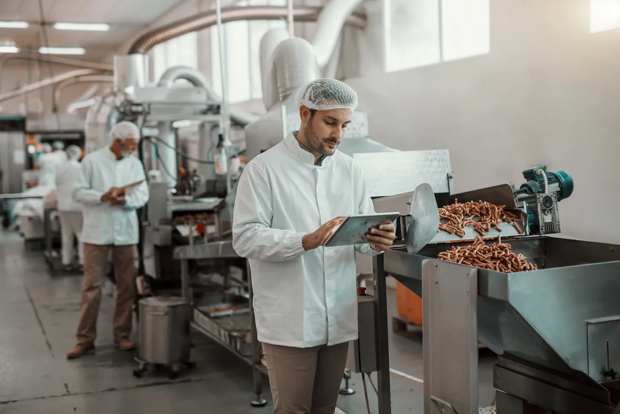 Un supervisor evalúa la calidad en planta de alimentos. La filtración del aire en esta industria es importante.