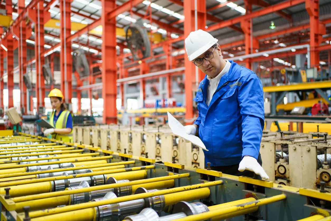 Ingeniero en casco blanco inspeccionando maquinaria en fábrica y hacer una lista de verificación.
