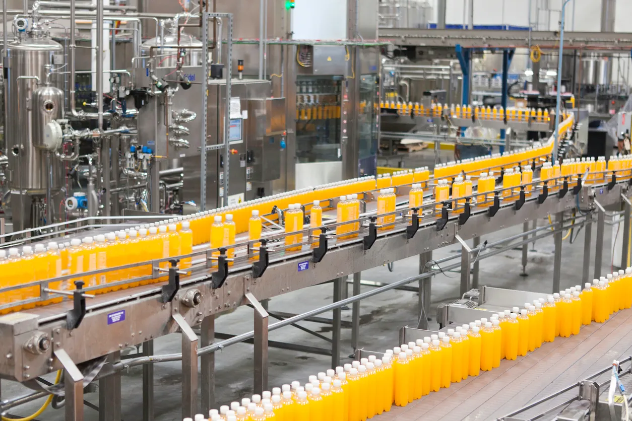 Botellas empaquetadas desplazándose por una cinta transportadora en la industria del embotellado.
