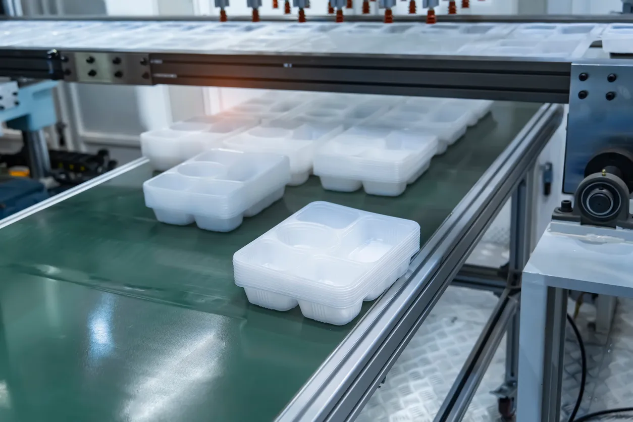 Pila de contenedores de alimentos de polipropileno en la cinta transportadora de la máquina automática de moldeo por inyecció