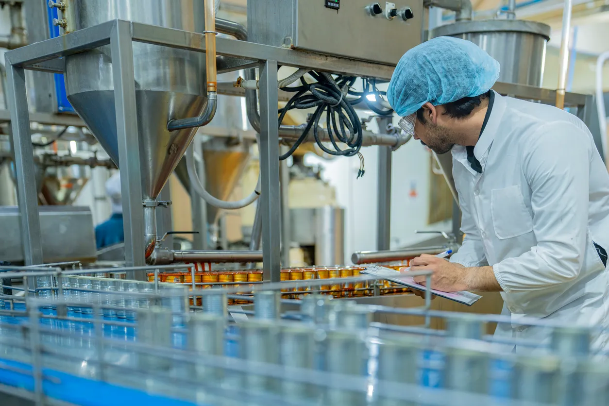 Un trabajador de fábrica inspecciona maquinaria avanzada en una moderna instalación de producción de alimentos, 