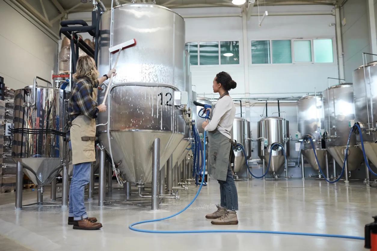 Par de jóvenes realizando la limpieza de equipos en industria