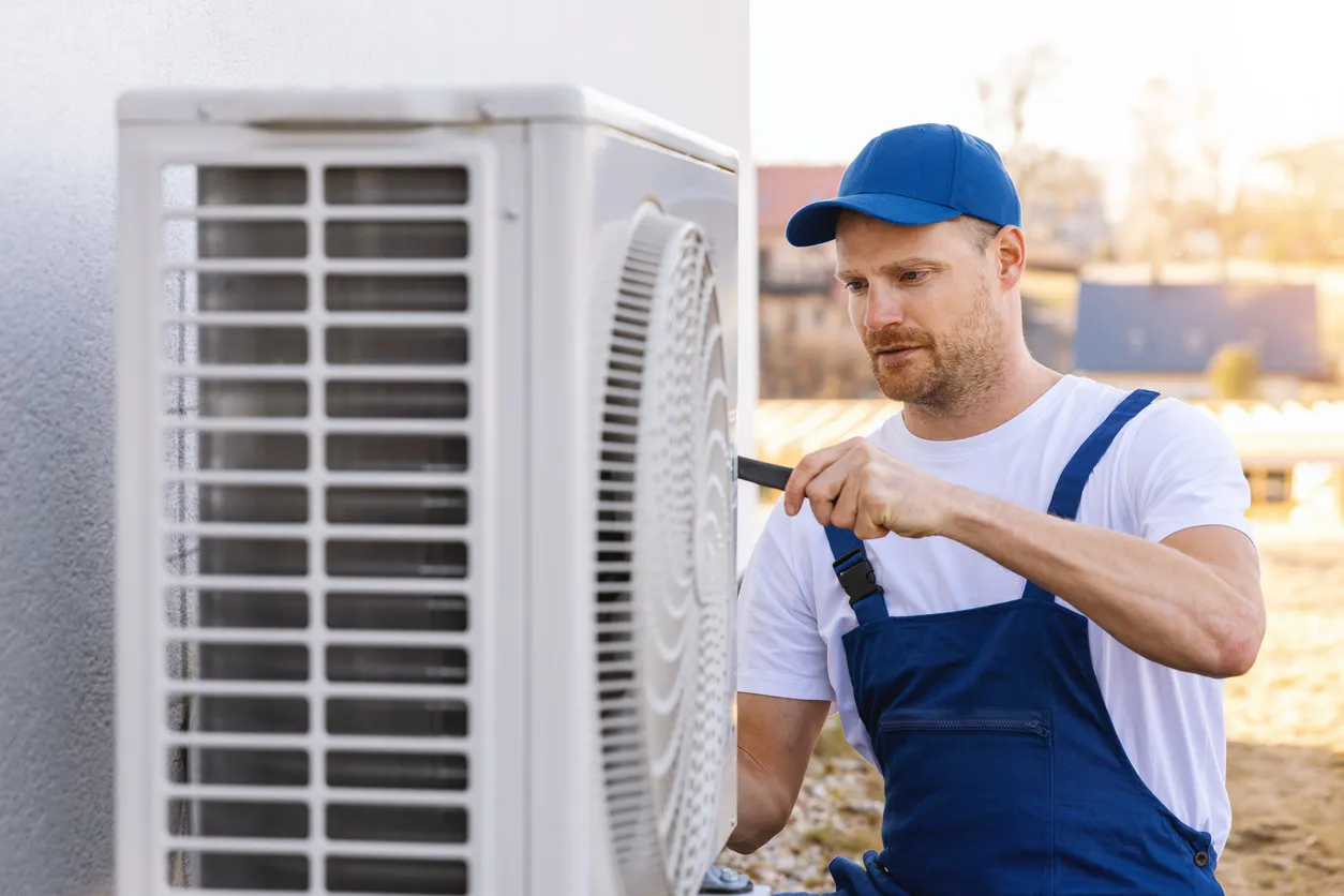 Técnico que trabaja con la unidad exterior de aire acondicionado o bomba de calor. Servicio, mantenimiento y reparación