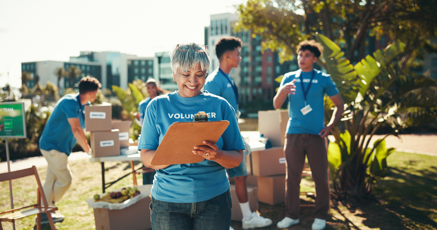 Feliz, voluntaria y mujer madura con portapapeles, caridad e inventario de donaciones, sonrisa y ong. Al aire libre, equipo y