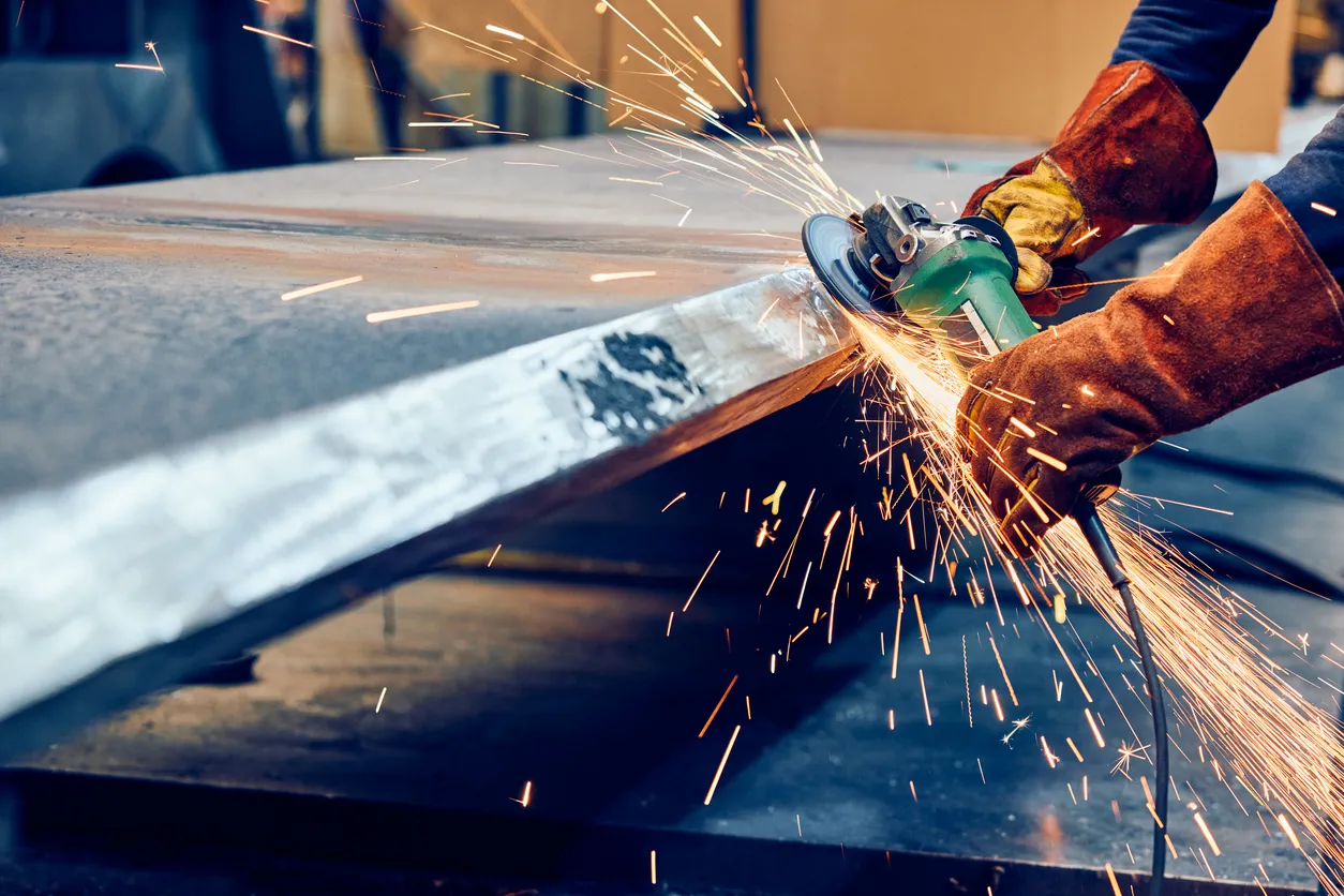 Trabajador industrial que rectifica la superficie metálica con lijadora neumática