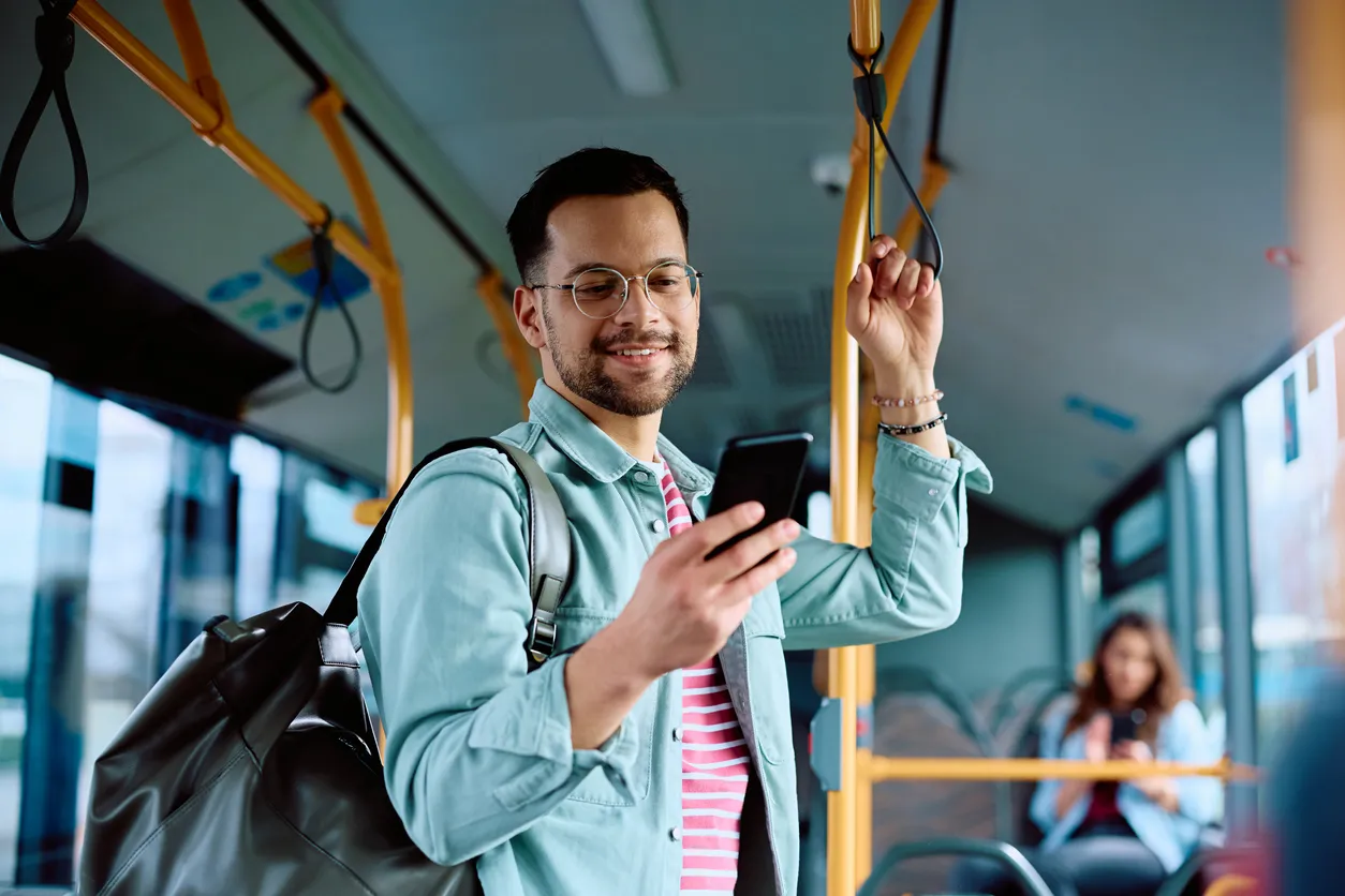 Un joven utiliza un teléfono móvil de media gama mientras viaja en transporte público.