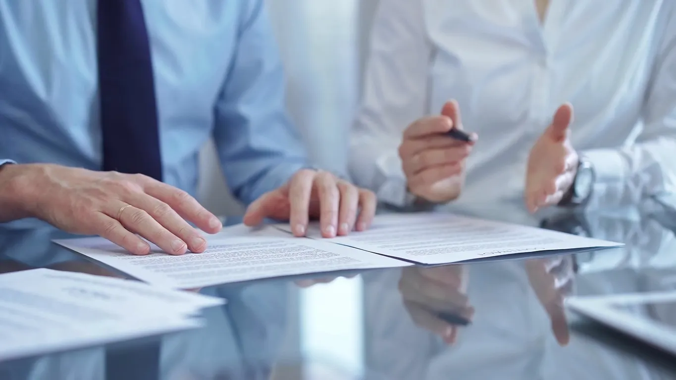 Diversos empresarios discutiendo los documentos del contrato antes de firmar.