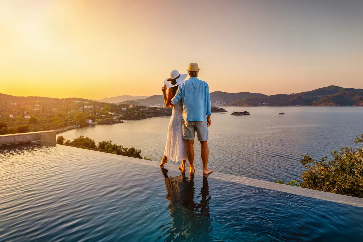 Una pareja romántica de vacaciones de verano, de pie junto a la piscina