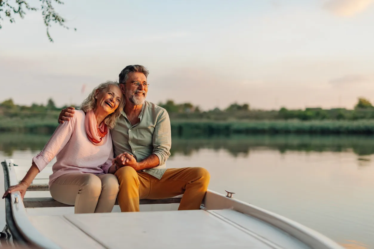 Feliz pareja de ancianos disfrutando de un romántico paseo en barco al atardecer 