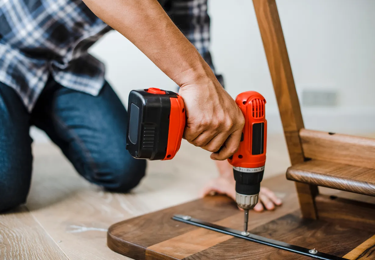Hombre usando un taladro de mano para montar una mesa de madera