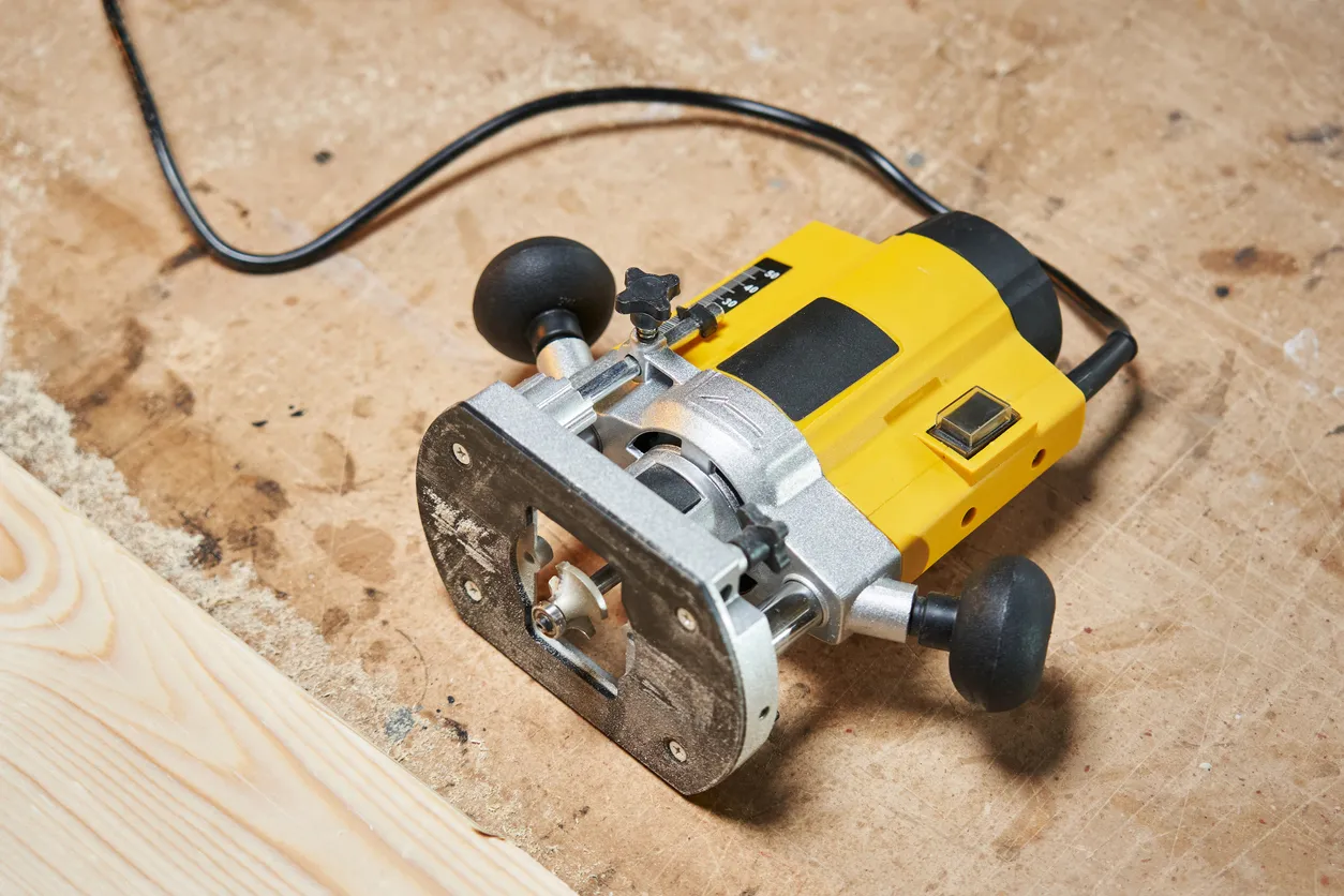 Vista superior de un enrutador eléctrico para trabajar la madera acostado en un banco de trabajo de madera