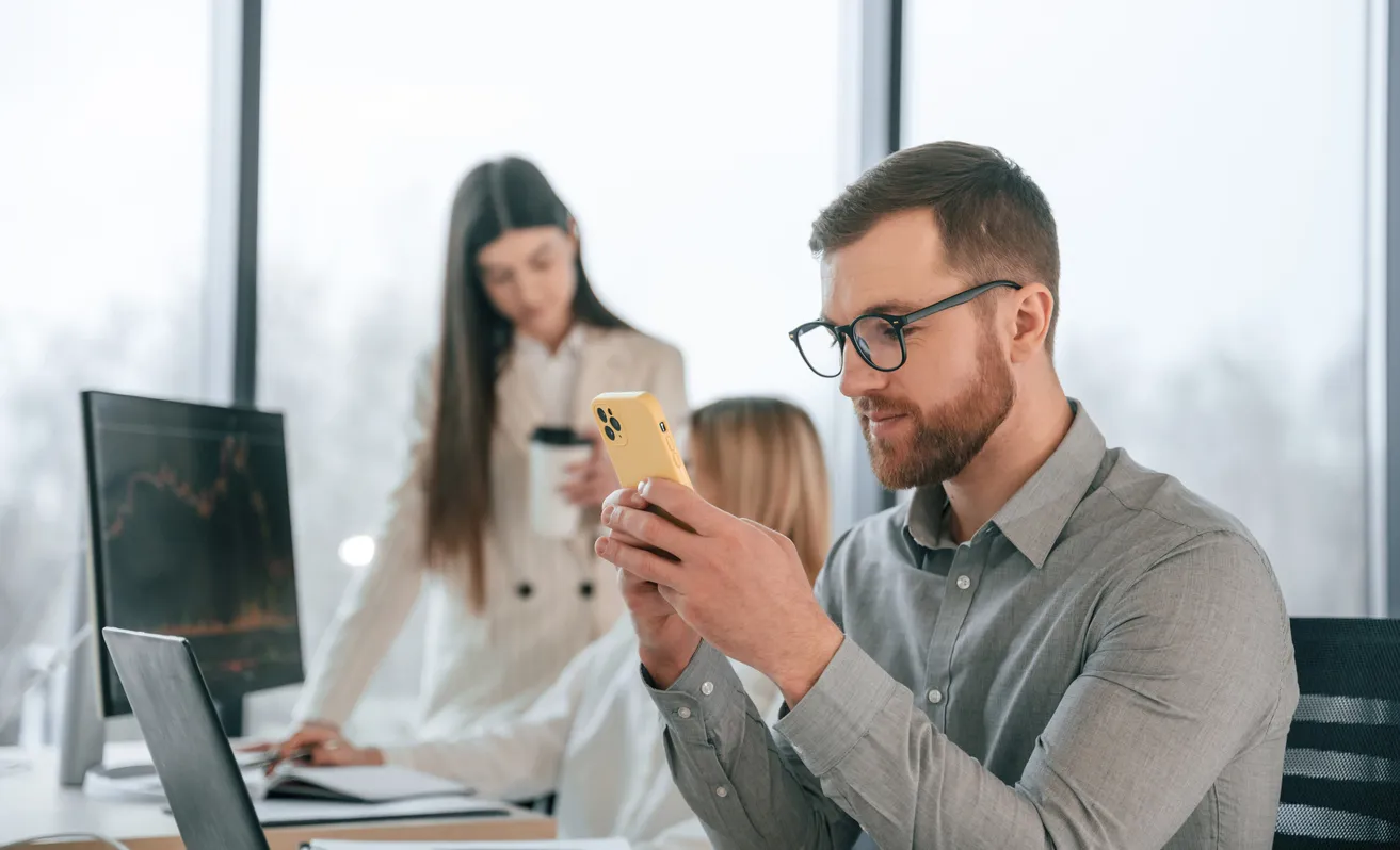 El hombre está sentado y usa un teléfono inteligente