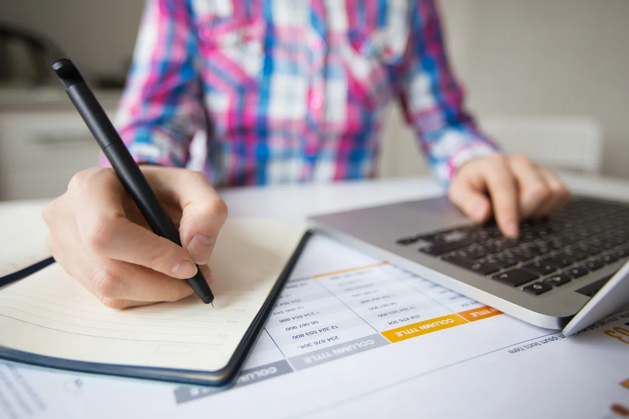 Persona de negocios trabajando en ordenador portátil y hacer notas