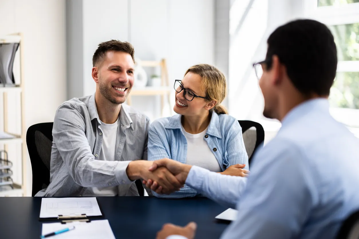 Pareja joven firmando contrato de alquiler con agente inmobiliario en la vista del apartamento