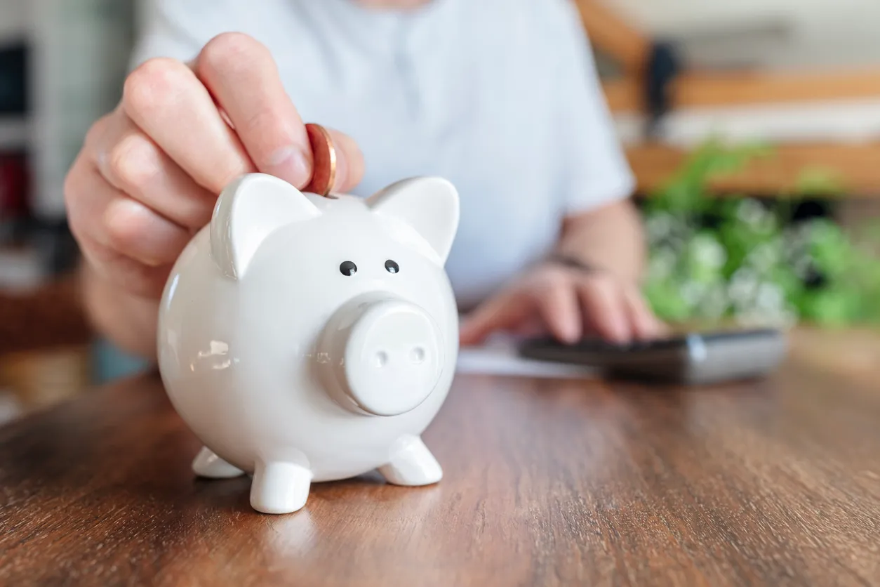 Ahorros de alcancía, hombre poniendo una moneda en una alcancía rosa 