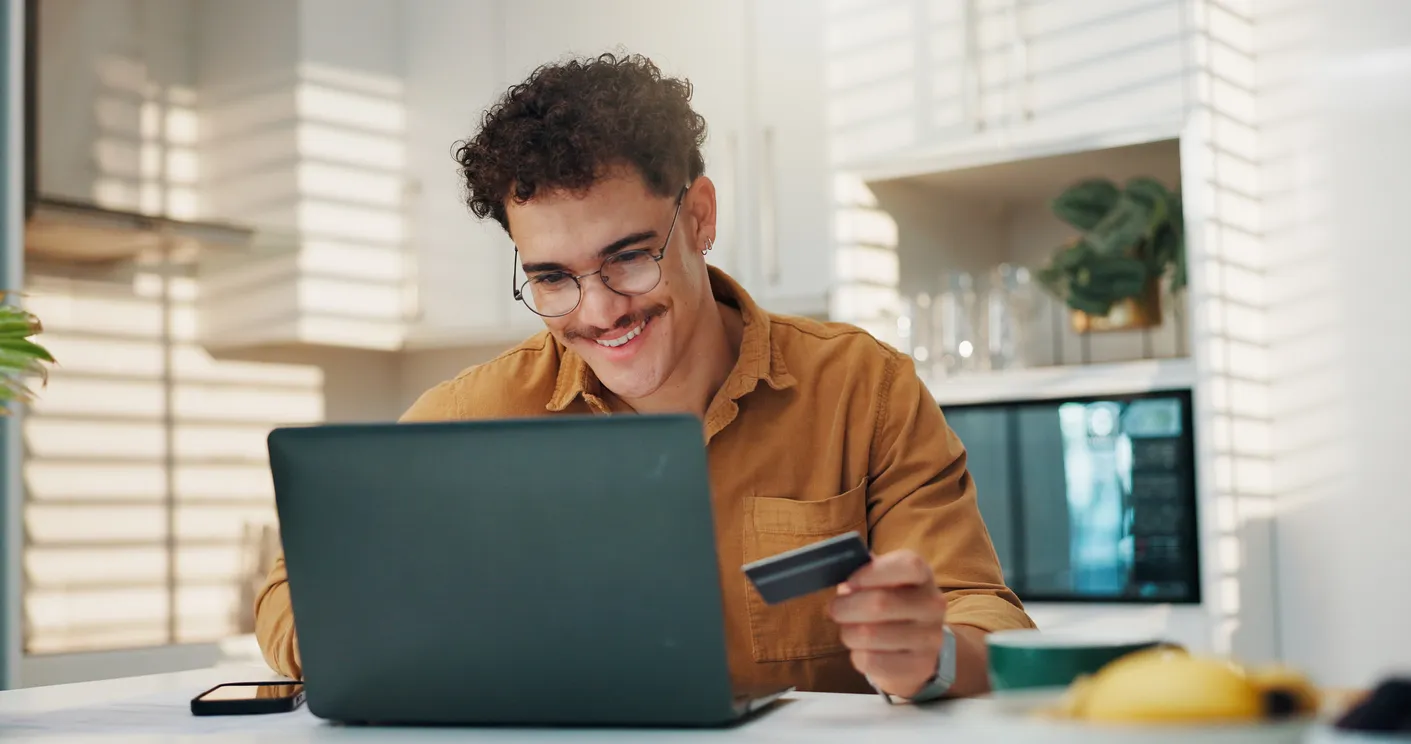 Hombre, tarjeta de crédito y feliz con la computadora portátil en casa para compras en línea, pago del carrito y código de cu