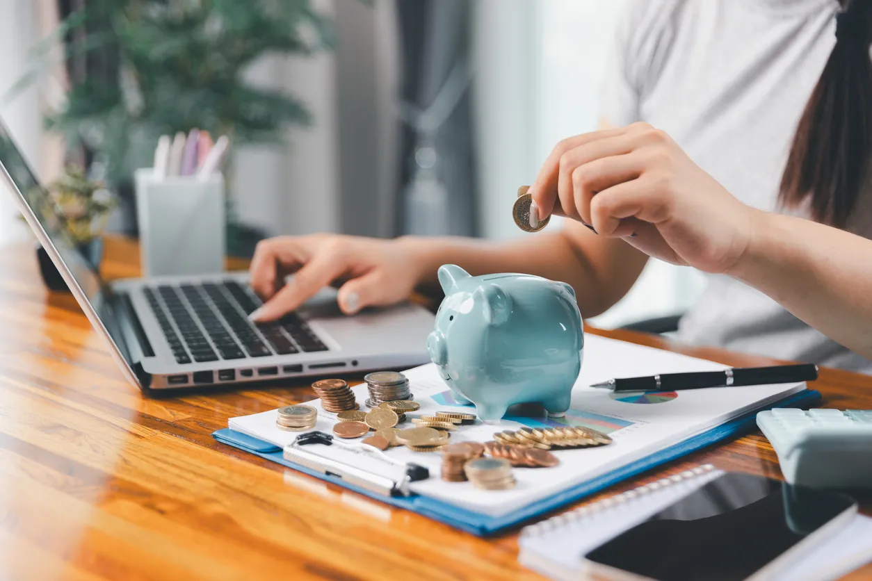 Mujer de negocios ahorrando dinero con alcancía y monedas en el escritorio