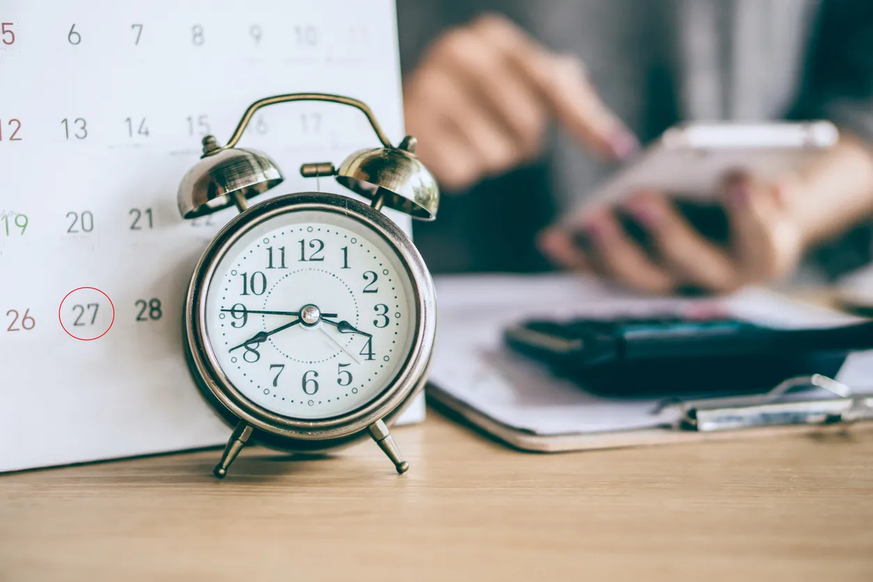 o Calendario y reloj despertador con desenfoque de negocio mujer mano calculando