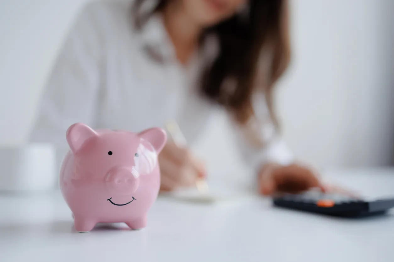 Ahorrar dinero con una alcancía mientras presupuestas en un espacio de trabajo 