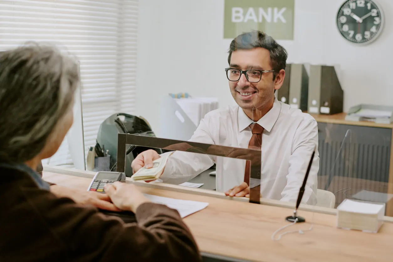 Cajero atendiendo a clienta en un banco 