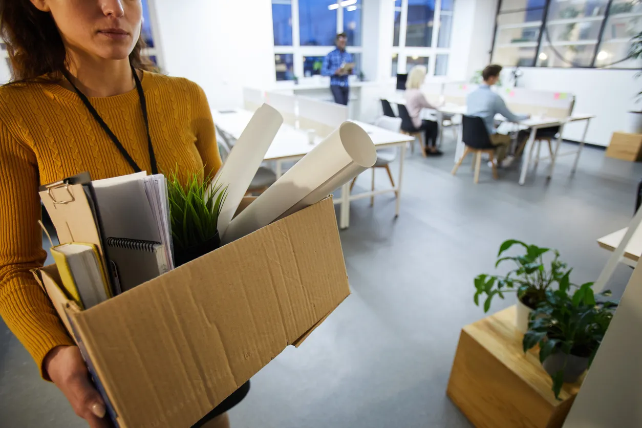 Salida de empleada con una caja en sus manos con sus cosas despues de renunciar