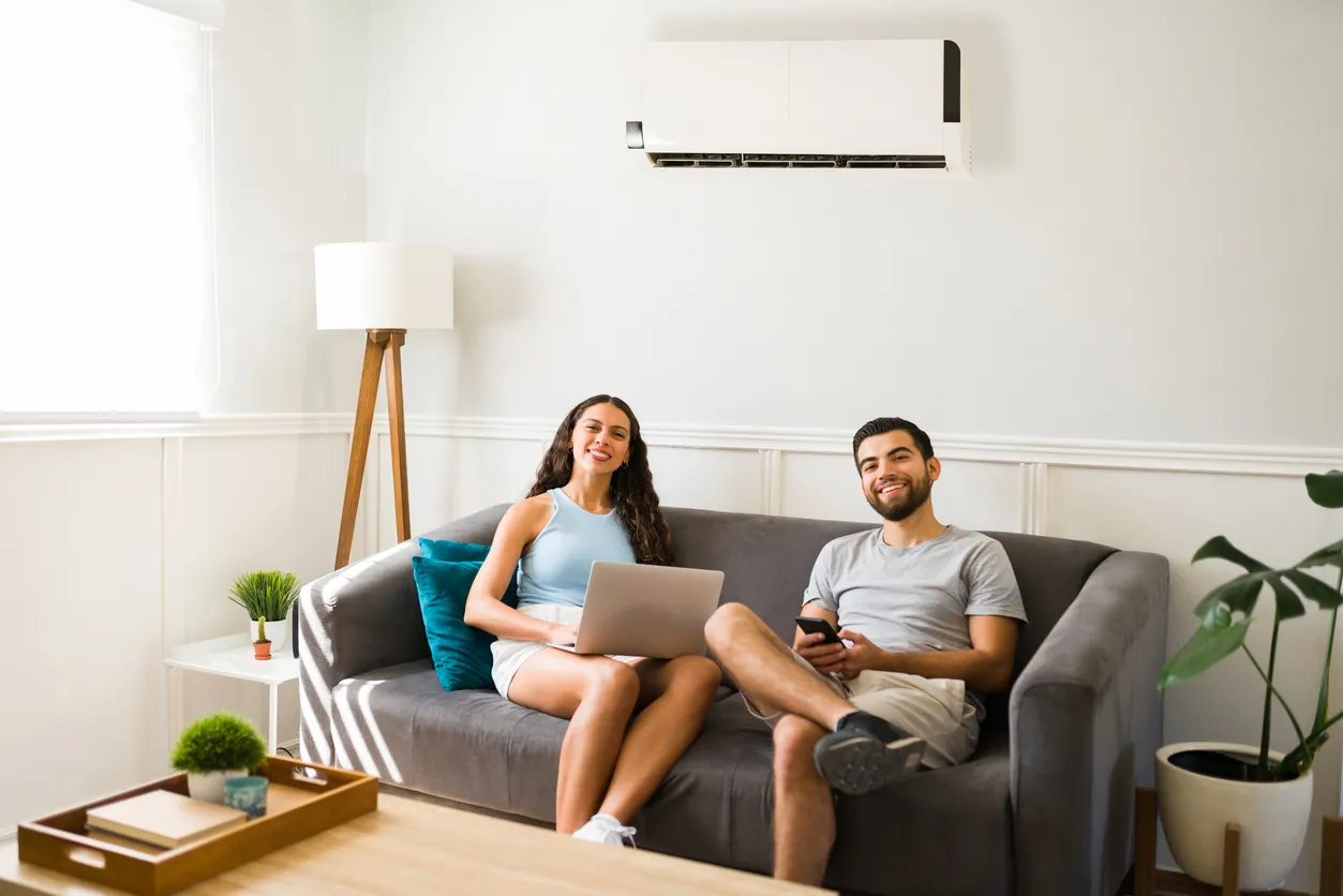 Pareja trabajando juntos en casa mientras disfrutan del aire acondicionado.