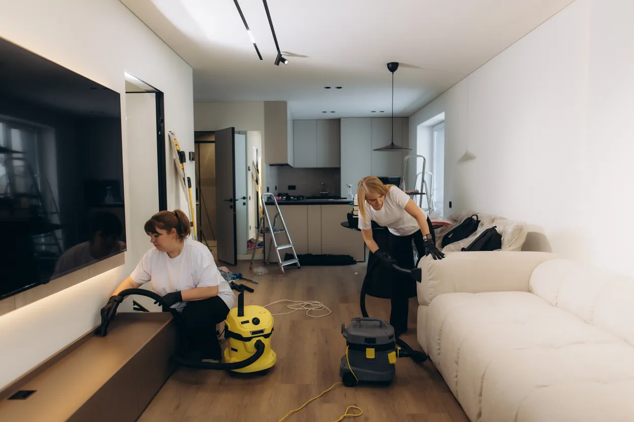 Limpiadores profesionales aspirando el salón de apartamentos modernos
