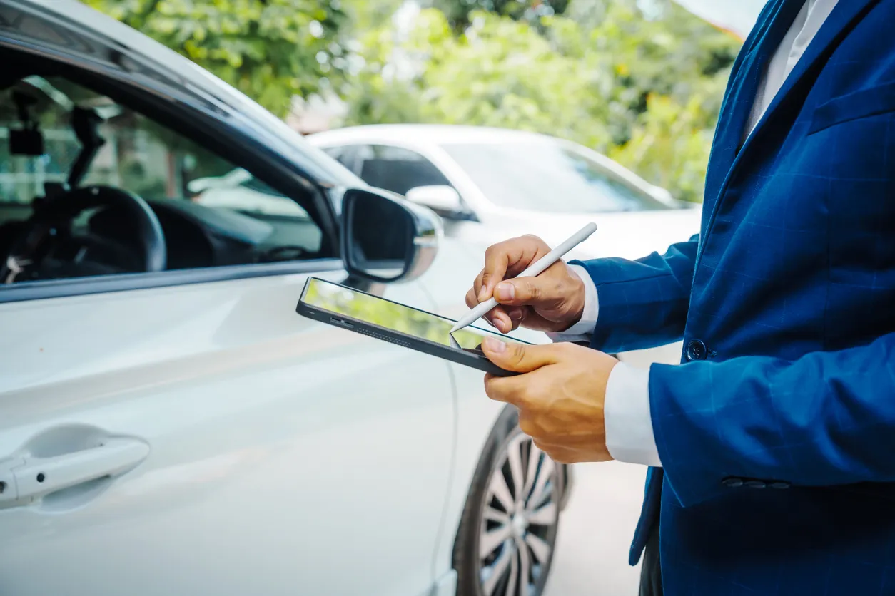 Hombre de negocios en traje y agente de seguros de automóviles evaluar los daños del automóvil, discutir el deducible, las re