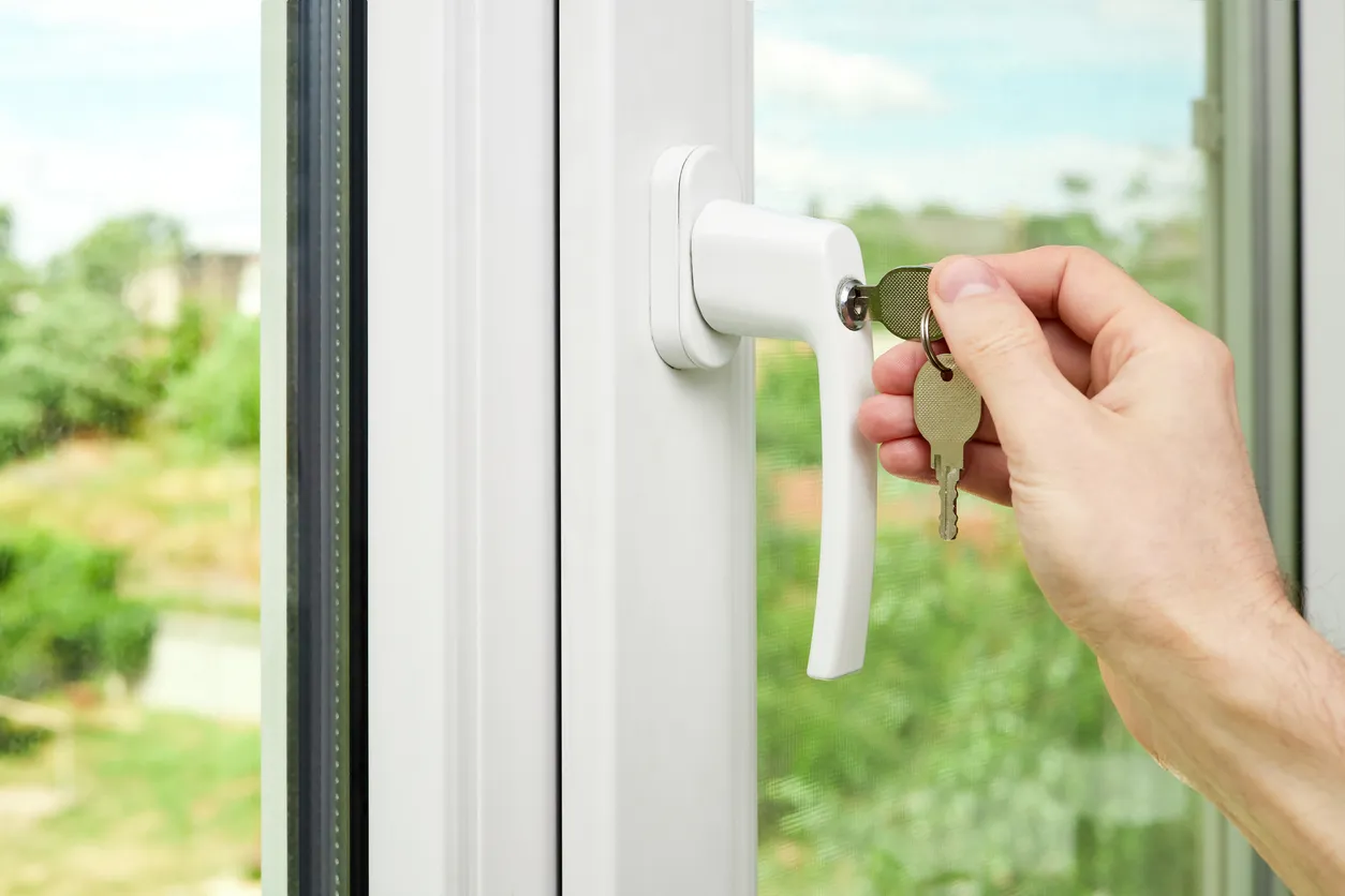 Un hombre cierra o desbloquea una ventana de plástico con llaves