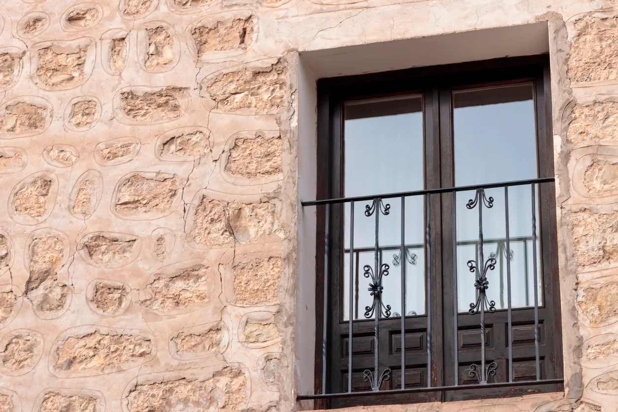 Edificio tradicional de muro de piedra con ventana de balcón de madera 