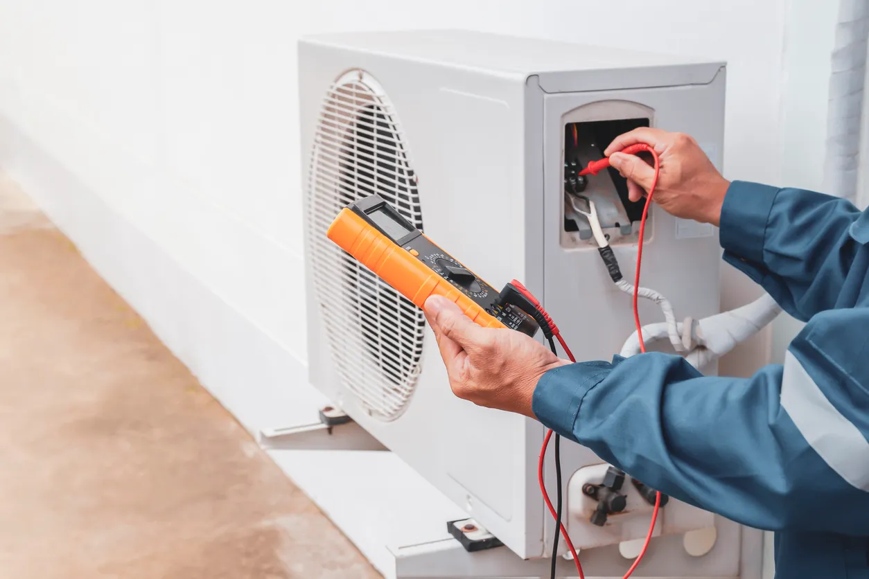 Técnico de aire acondicionado que repara el sistema de aire acondicionado central con herramientas para exteriores