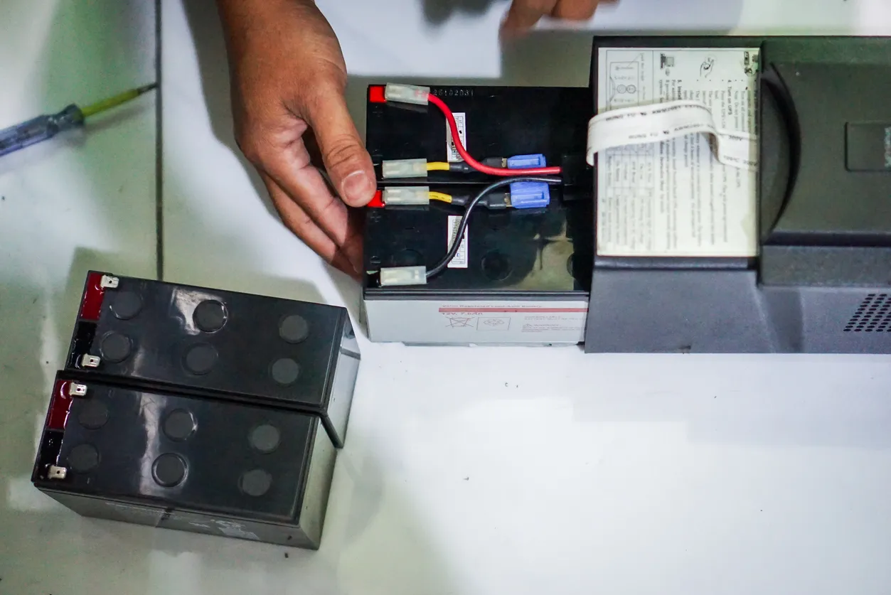 Un hombre instalando un paquete de baterías de repuesto para una fuente de alimentación ininterrumpida