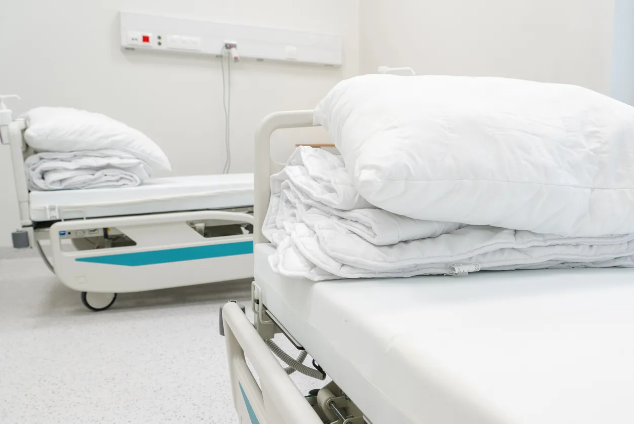 Camas con sábanas y almohadas blancas en hospital