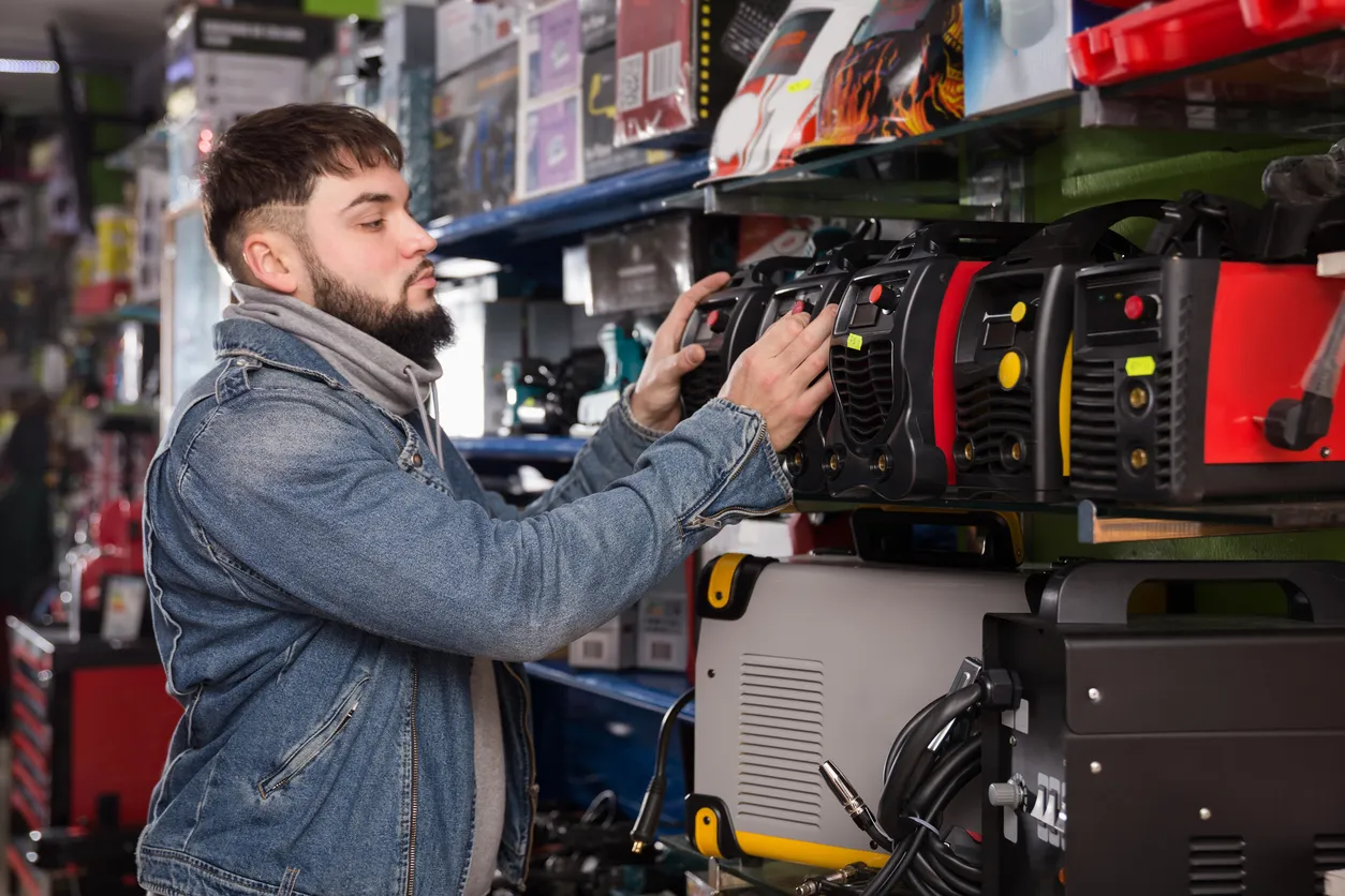 Hombre elige máquina de soldadura en tienda 
