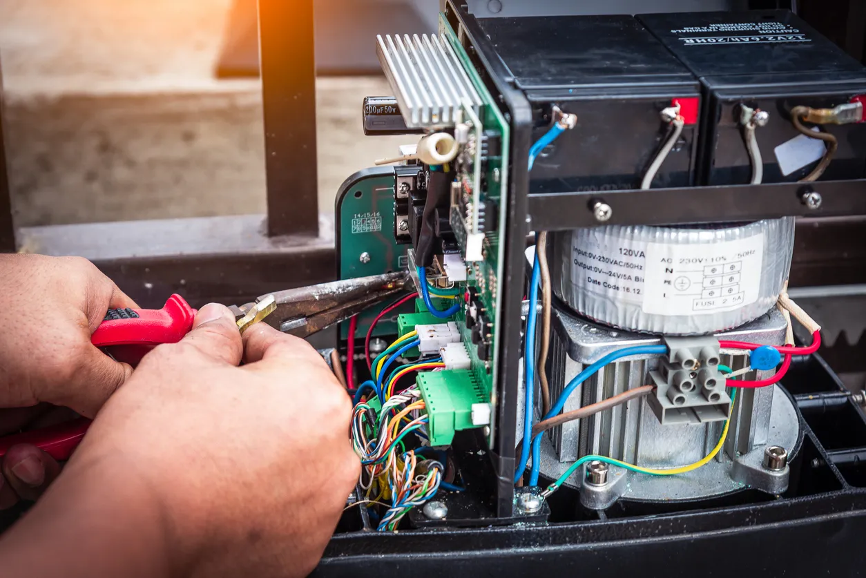Técnico ensamblando y probando el panel de control eléctrico en el motor de control de puerta automática