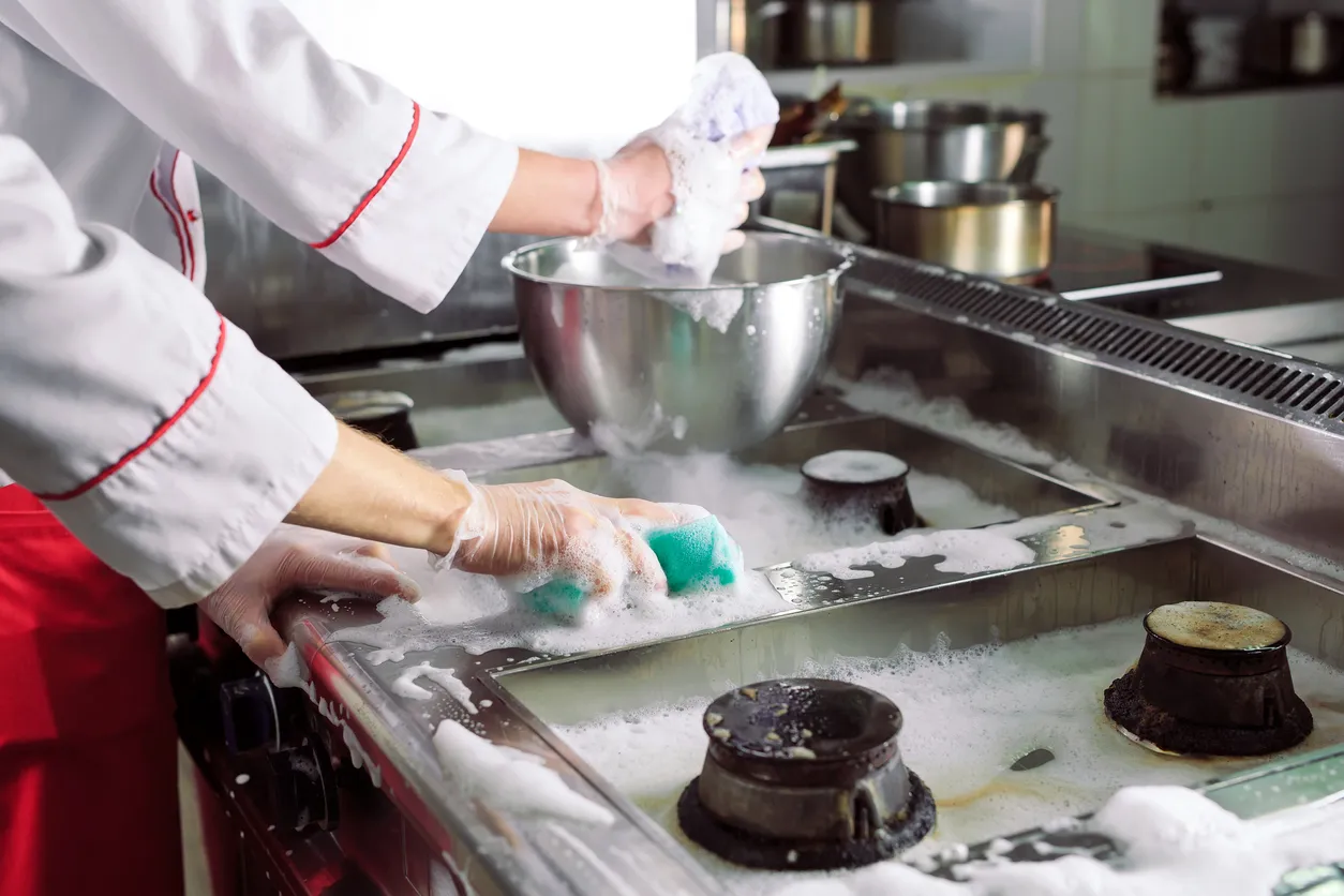 Los cocineros lavan el horno, la estufa y el extractor del restaurante.