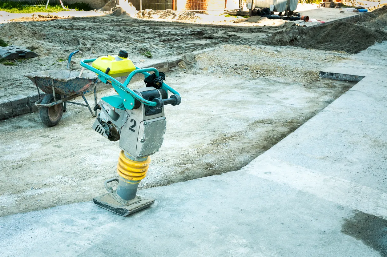El equipo de construcción está listo para compactar el suelo en un sitio de construcción en una zona urbana bulliciosa duran