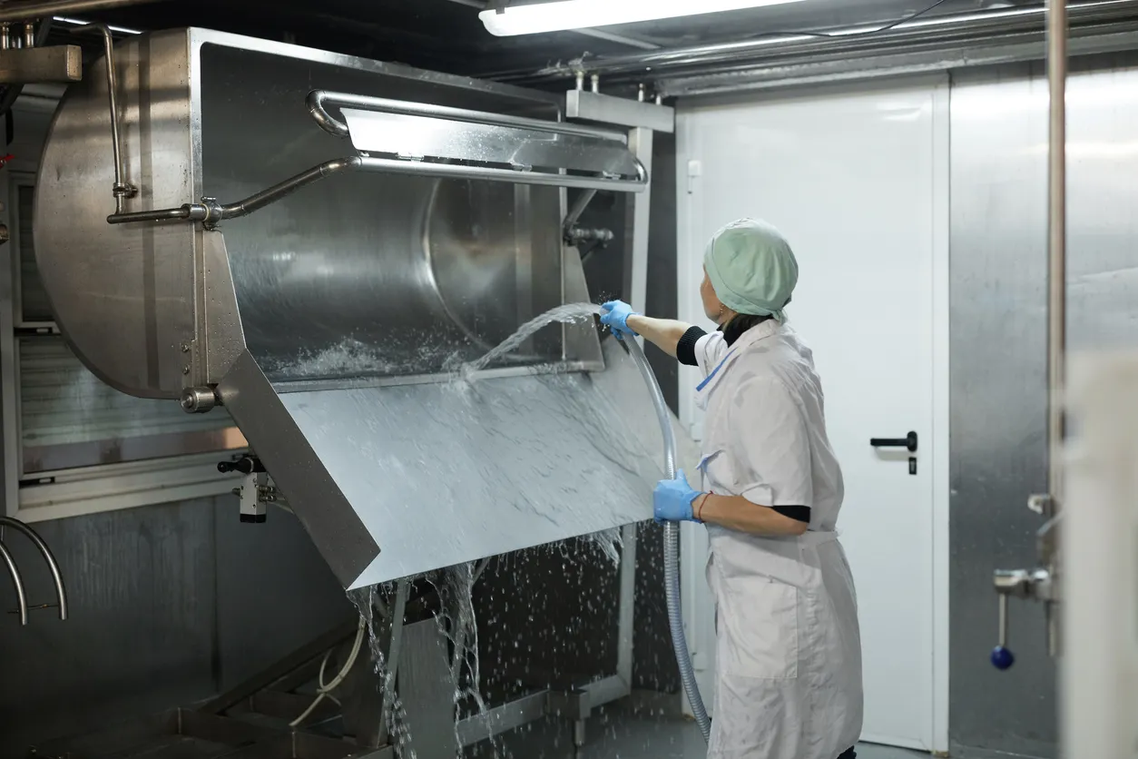 Trabajadora lavando un tanque en una fábrica de quesos y lácteos