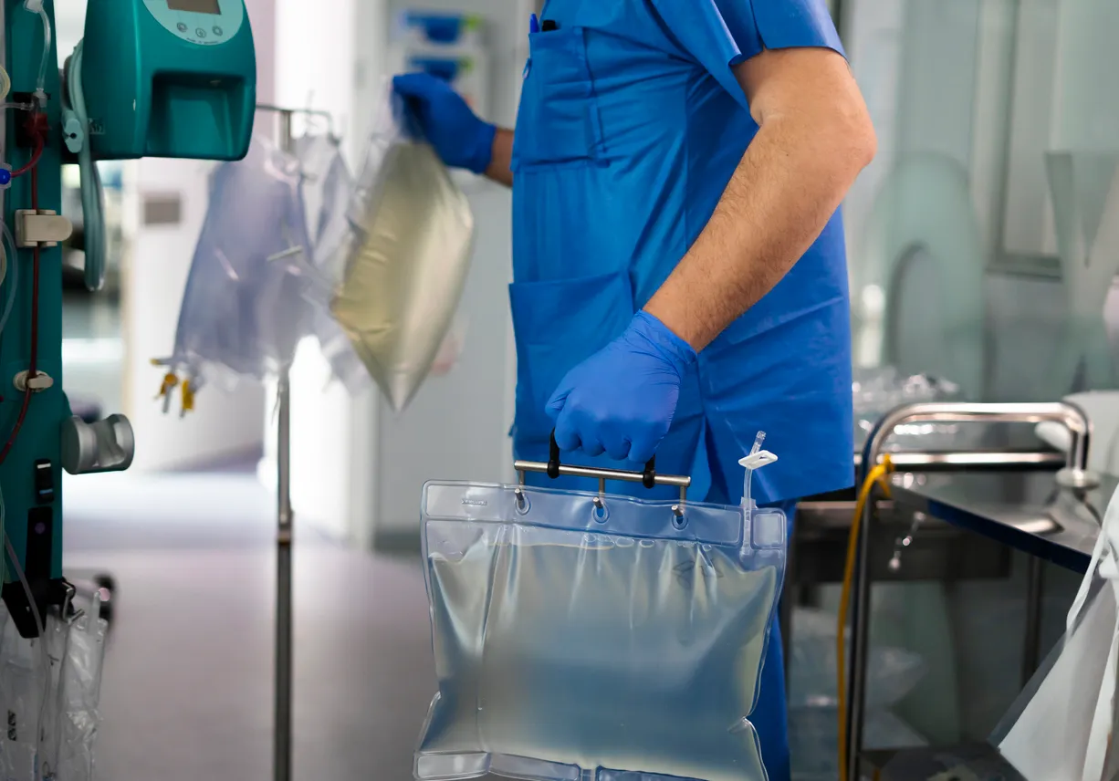Médico manipulando bolsa de fluidos intravenosos en un entorno hospitalario