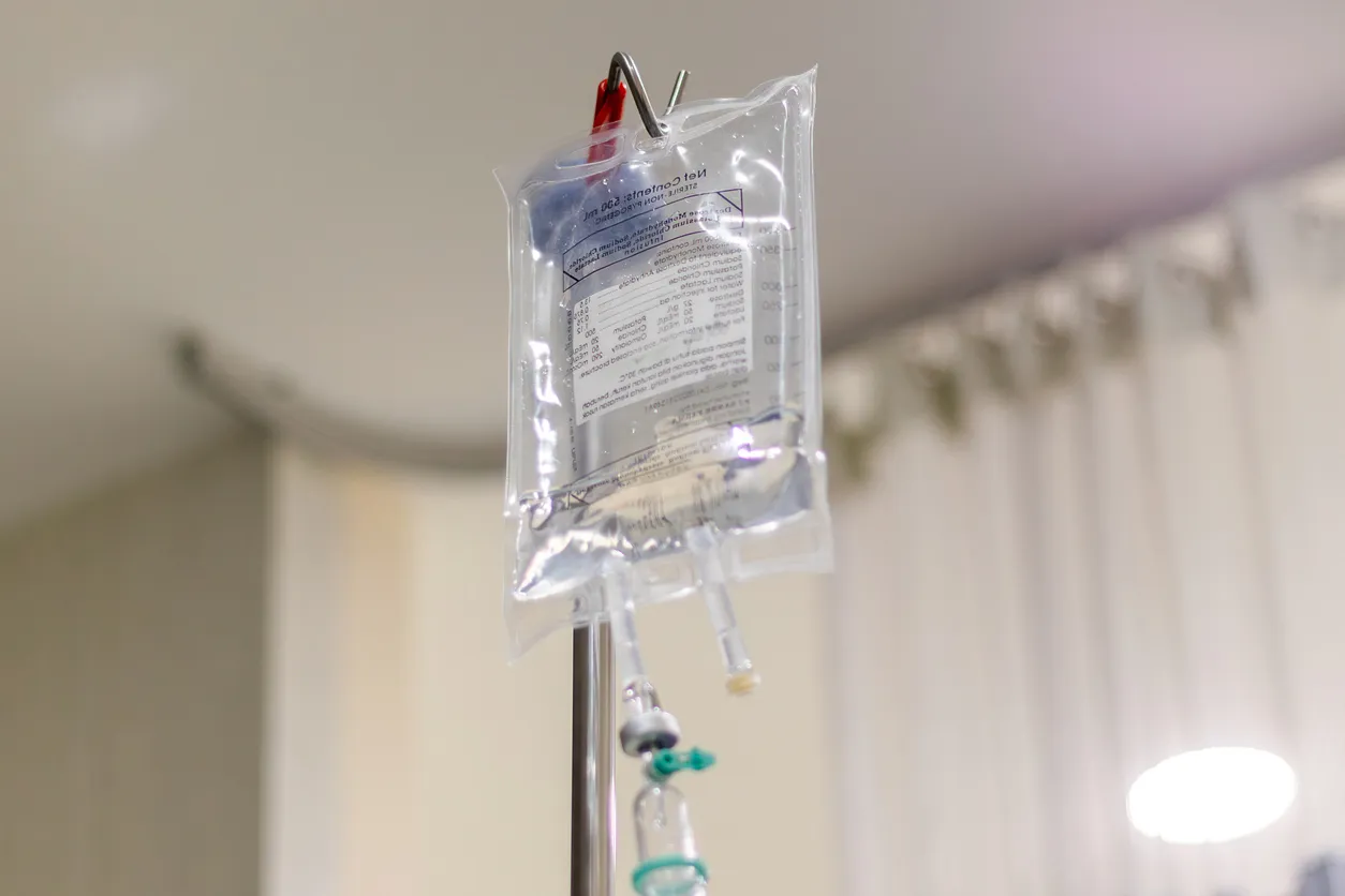 Solución de infusión colgada de un poste de metal en la habitación de pacientes hospitalizados del hospital