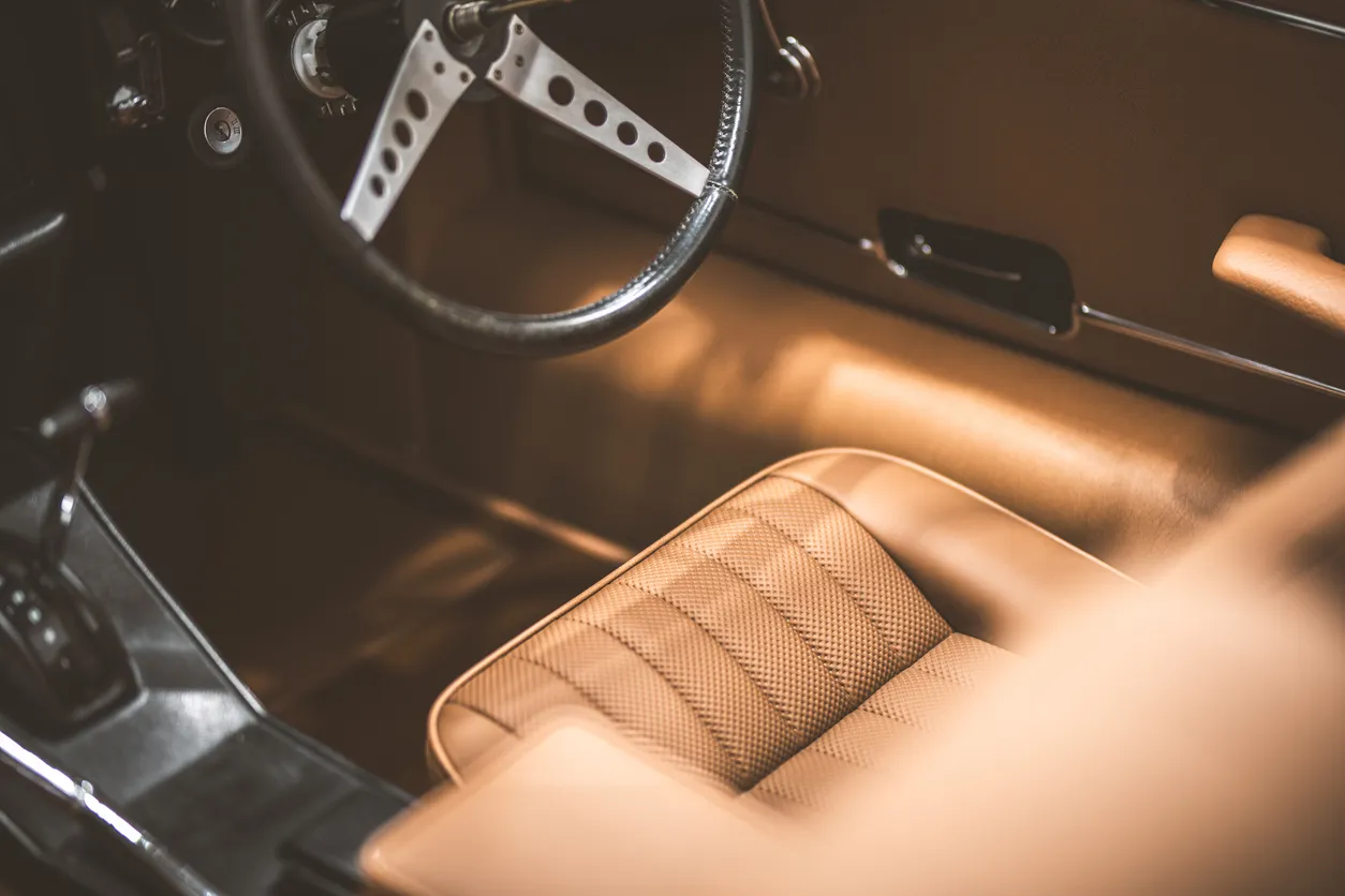 Primer plano del interior de un coche antiguo con asientos de cuero y volante clásico