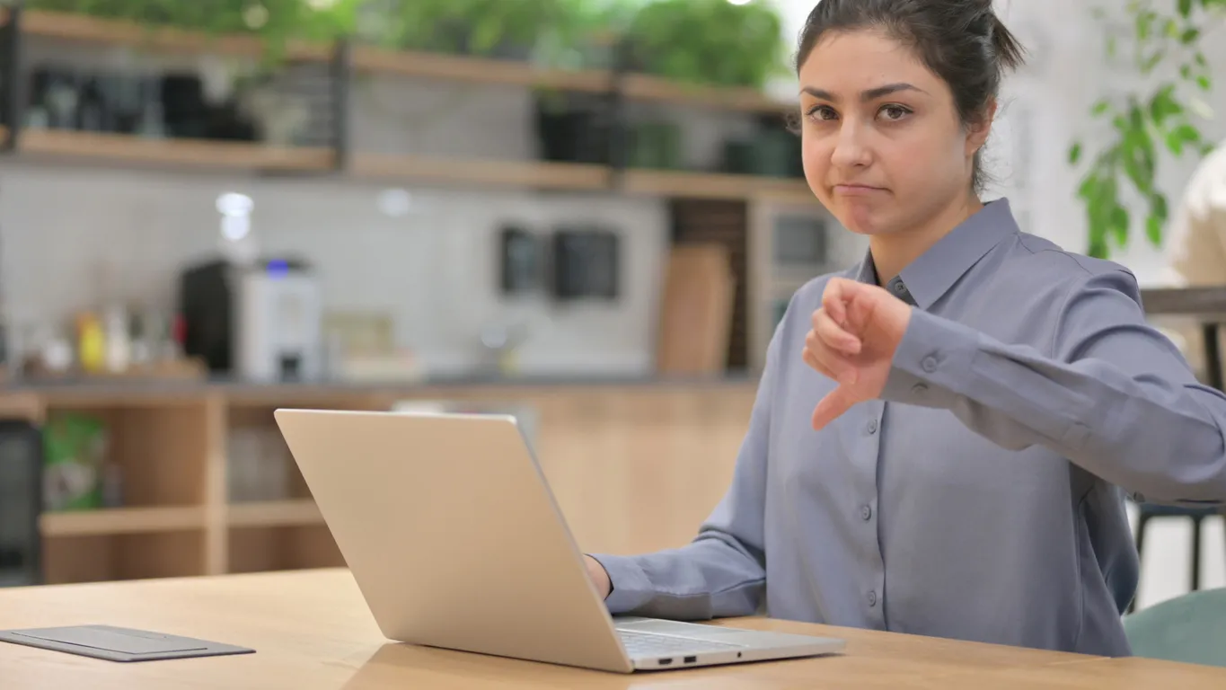 Mujer con computadora portátil que muestra pulgares hacia abajo