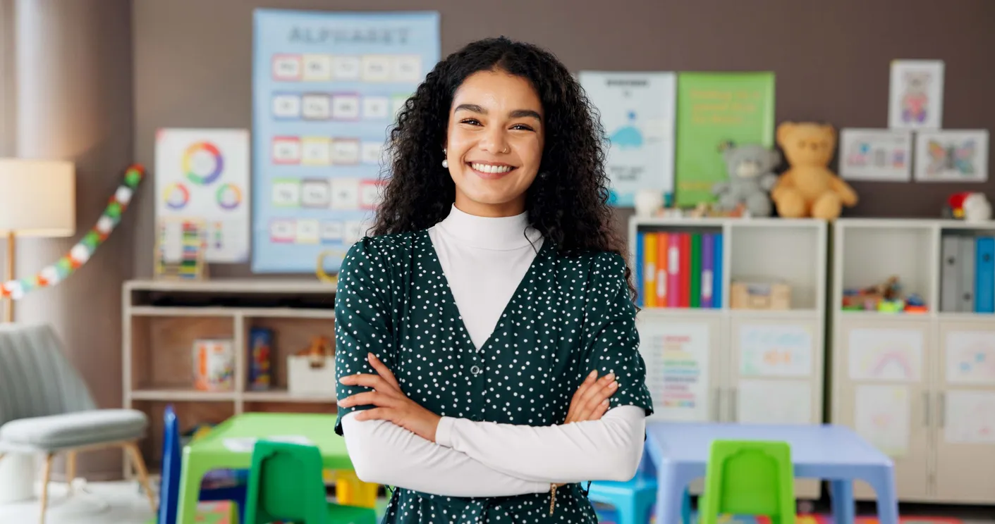 Mujer, maestra y retrato en el aula con confianza, sonrisa y montessori sobre nosotros. Educador, jardín de infantes y brazos