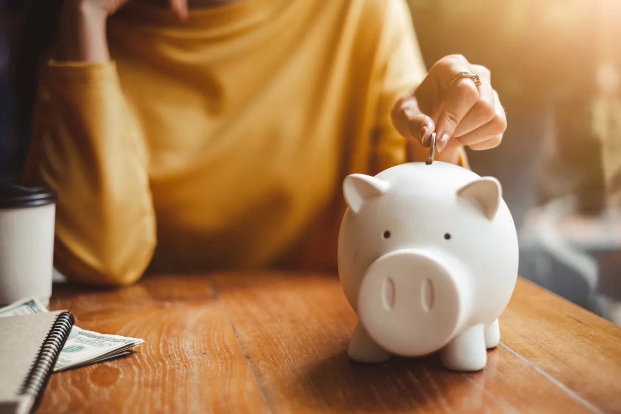 Mano de mujer poner dinero moneda en la alcancía para ahorrar dinero riqueza y concepto financiero