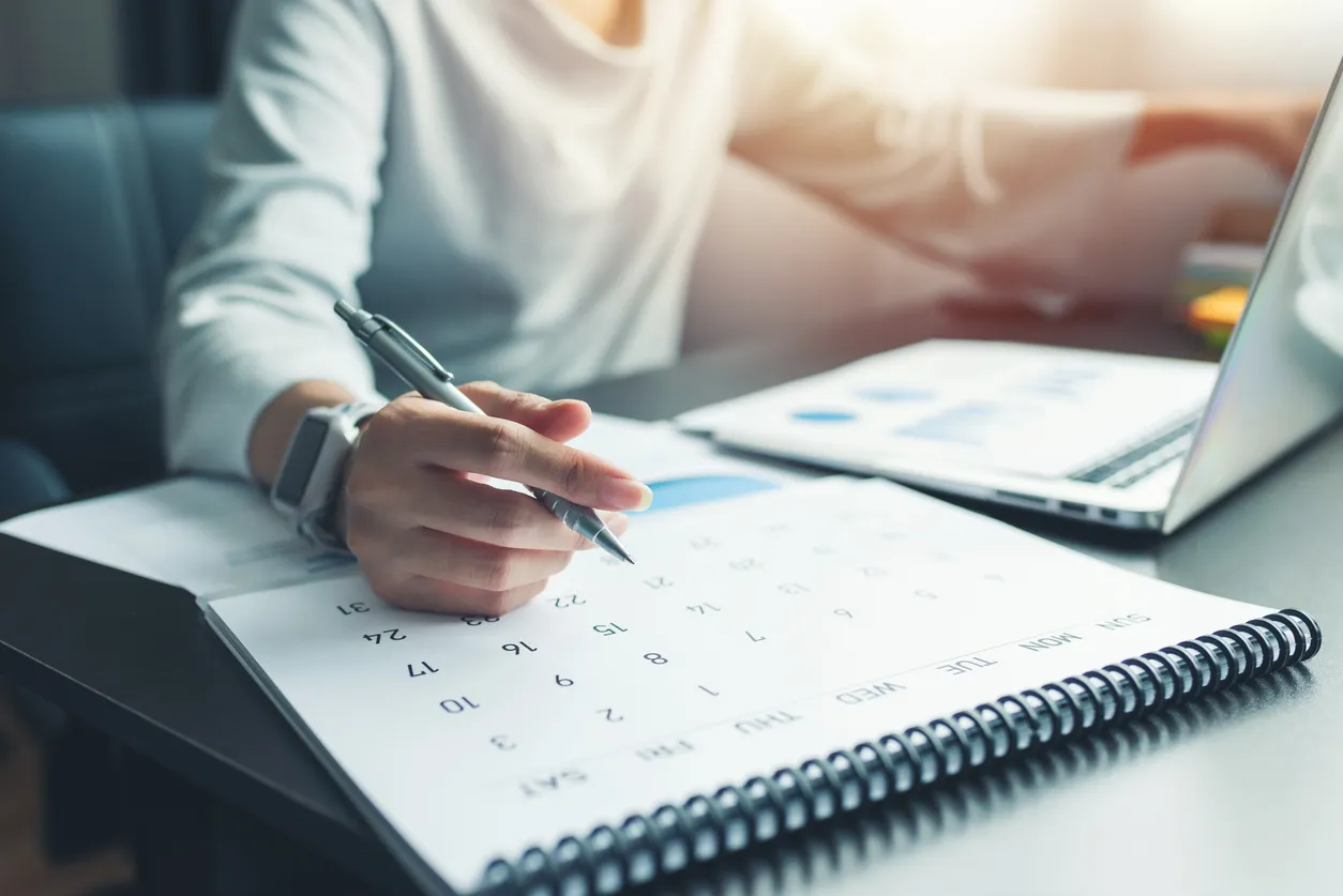 Mujer de negocios sentada trabajando y pensando para planificar el evento con calendario y portátil