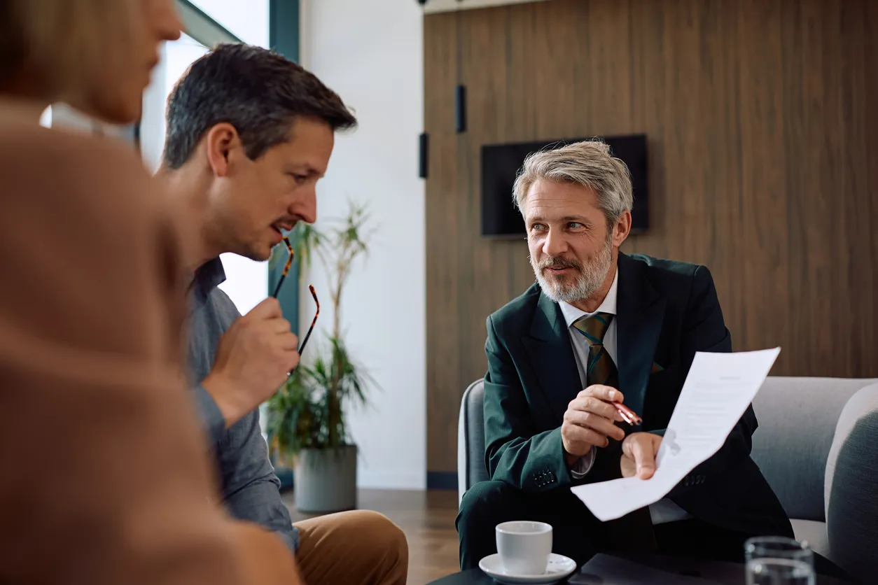 Un sonriente asesor financiero revisando la documentación con sus clientes durante la reunión