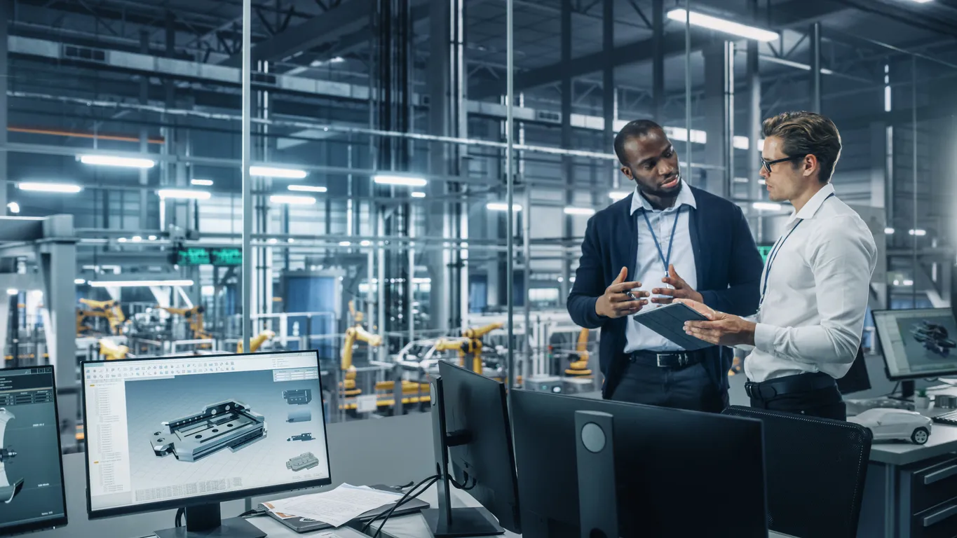 Dos diversos ingenieros industriales automotrices hablando sobre la producción de vehículos mientras están de pie 