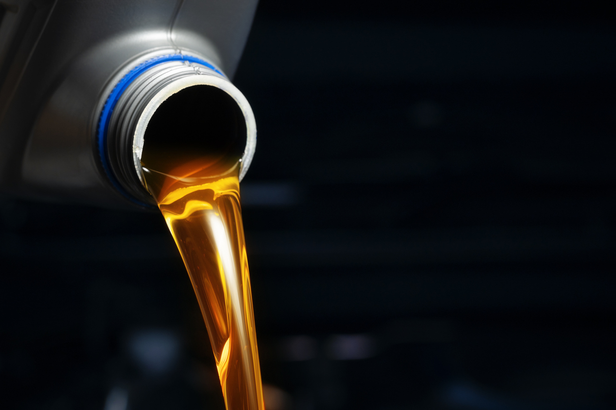 Vierta aceite de motor de la botella de lubricante. Antecedentes del motor, taller de cambio de aceite, industria de servicio